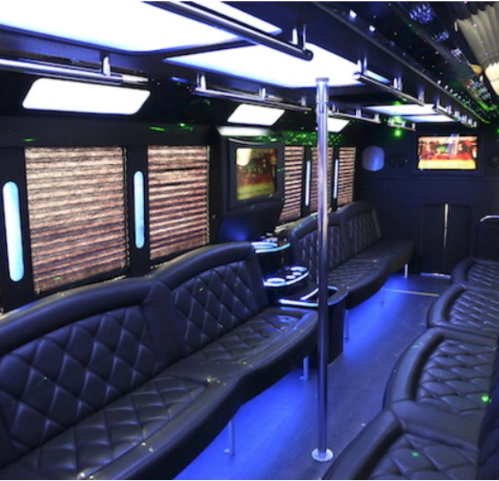 Arvada Limo 5 Inside of a luxury party bus with plush black leather seats and a stripper pole in the middle.